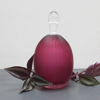 View and buy handmade glass homewares by Catriona MacKenzie at The Biscuit Factory. Image shows a pink opaque vase with a clear top, surrounded by leaves.