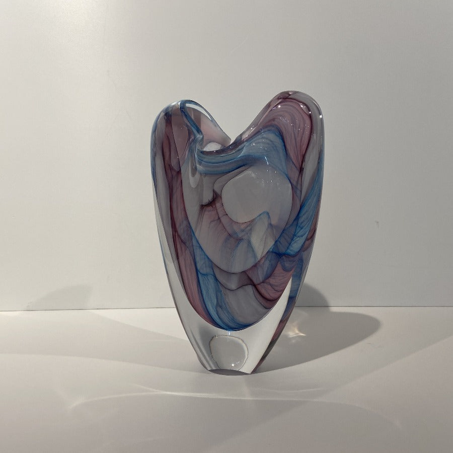 Buy 'Pastel Georgia V Form' glass vase by Peter Layton online at The Biscuit Factory. Image shows a glass vase with a 'V' shape. It has swirls of light blue, pink and white colour beneath the clear surface.