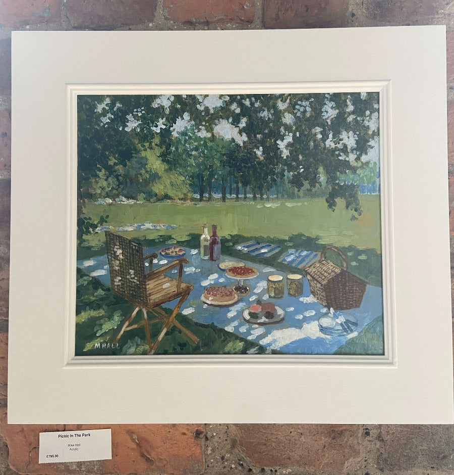 Picnic in the Park by Mike Hall, an original painting showing a picnic set in a sunny parkland, in a white frame. | Original art for sale at The Biscuit Factory Newcastle
