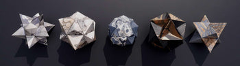 Image shows five geometric sculptures by Lousia Boyd. Each is a different 3D geometric shape and their surface is a combination of marbling and mark making in grey and white, and in orange and black.