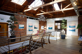 A couple choosing a painting to buy from a selection of landscape paintings.