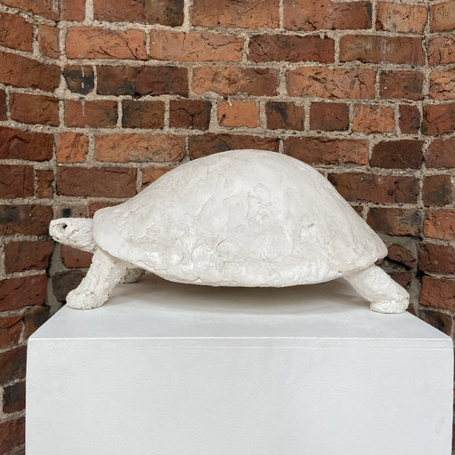 'Buy 'Tortoise' original mixed media handmade sculpture by Zoe Robinson online at The Biscuit Factory. Image shows a white mixed media sculpture of a tortoise displayed on a plinth against a brick wall.'