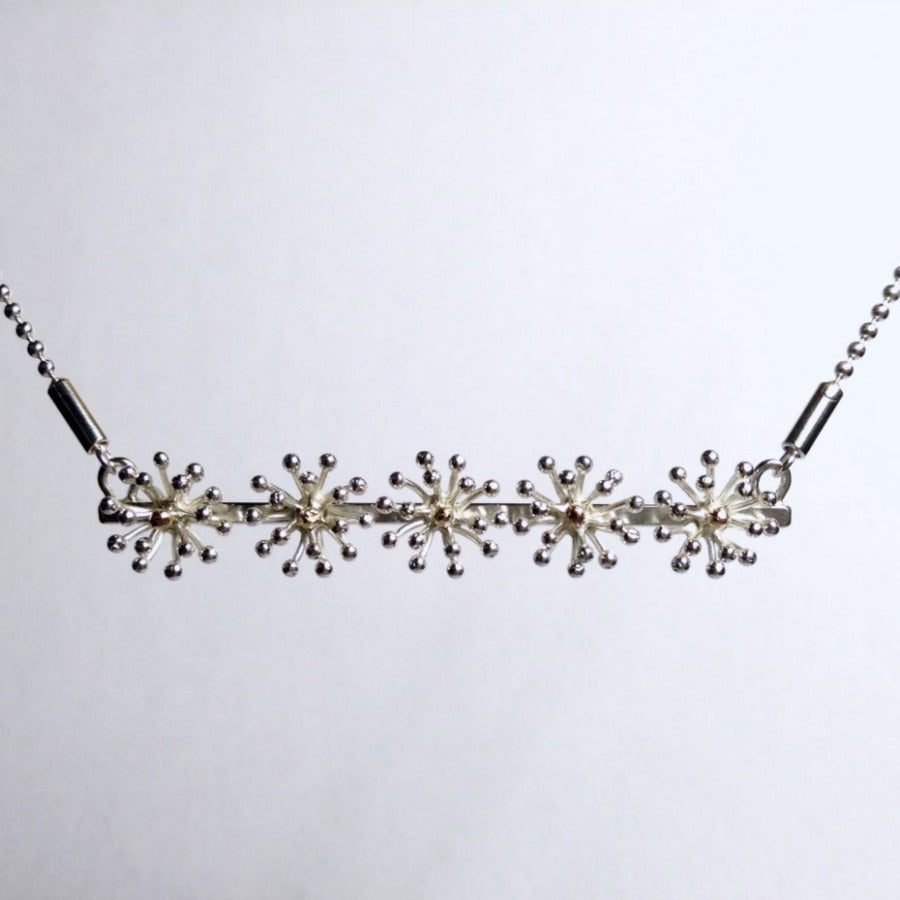 Fennel necklace by Yuki Kokai for sale at The Biscuit Factory. Image shows a silver necklace made of five fennel blower shapes on a silver bar hanging from a chain at each end,