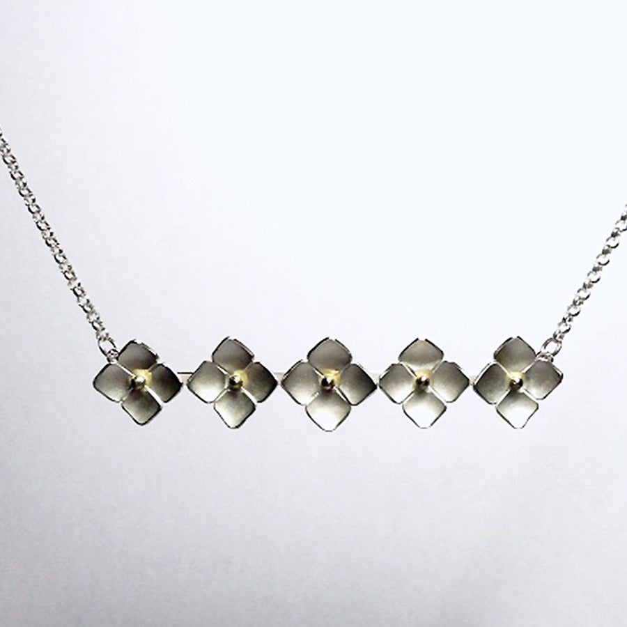 Image shows 'Hydrangea' necklace by Yuki Kokai, a silver and gold necklace made of five hydrangea flowers in a line, on a silver chain. For sale at The Biscuit Factory art  galleyr.