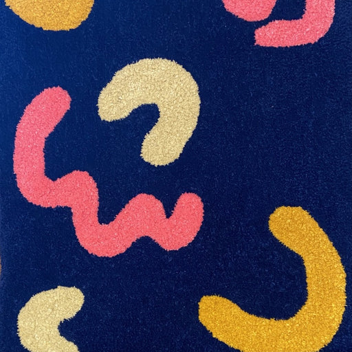 'Joy' by textile designer Loop and Yarn. Image shows part of a dark blue rug with cream, yellow and pink shapes.