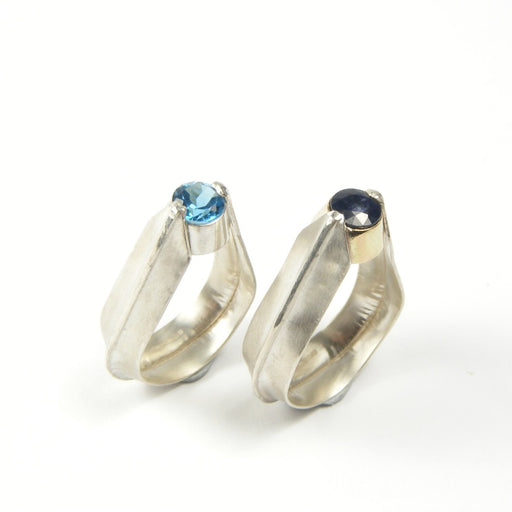 Shard Rings by Nettie Birch at The Biscuit Factory. Image shows two silver rings, one with a round topaz stone, the other with a black sapphire stone at the top.