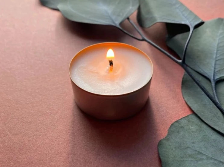 Sundrenched aromatherapy candles by Bous Candles, a single lit tealight candle on a pink surface. | Original handmade gifts at The Biscuit Factory Newcastle.