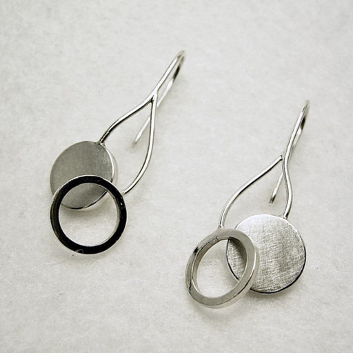 Swinging Vine earrings by Yuki Kokai for sale at The Biscuit Factory art gallery. Image shows a pair of silver earrings comprised of a silver disc and a ring attached to a silver hook, on a white background.
