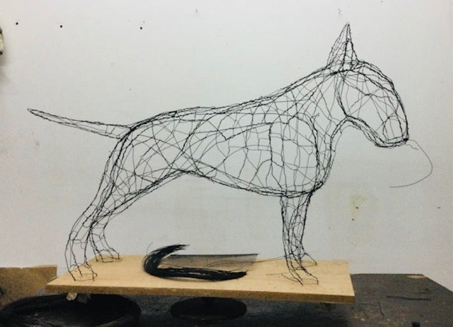 Create a Wire Dog Workshop at The Biscuit Factory Newcastle. Image shows a sculpture of a bull terrier dog made in black wire on a wooden stand by artist Zoe Robinson